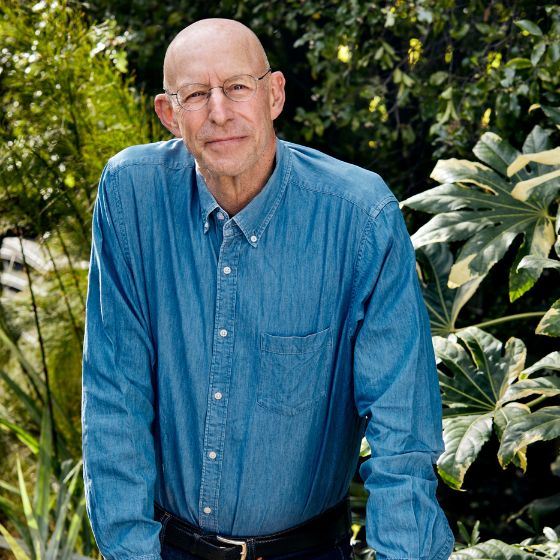 Photo of the author Michal Pollan taken by TABITHA SOREN. He is wearing a blue shirt and glasses.