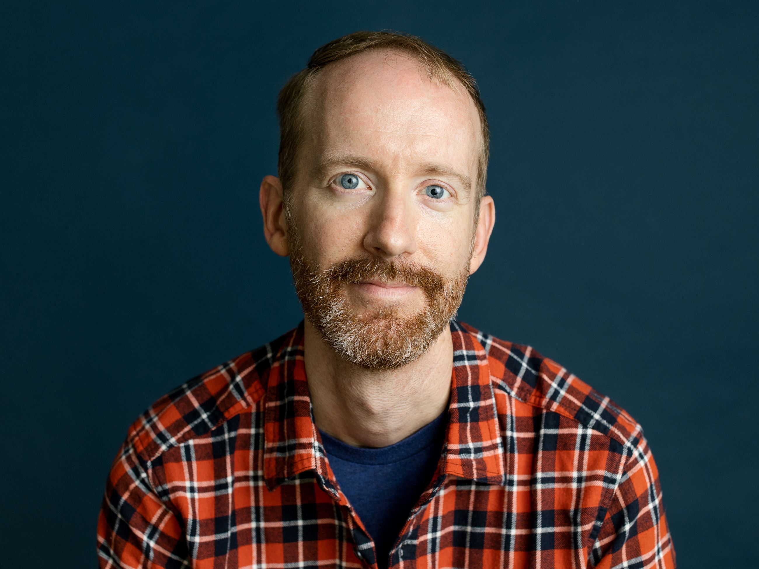 Author photo of Nate Powell. He is wearing a red plaid shirt.